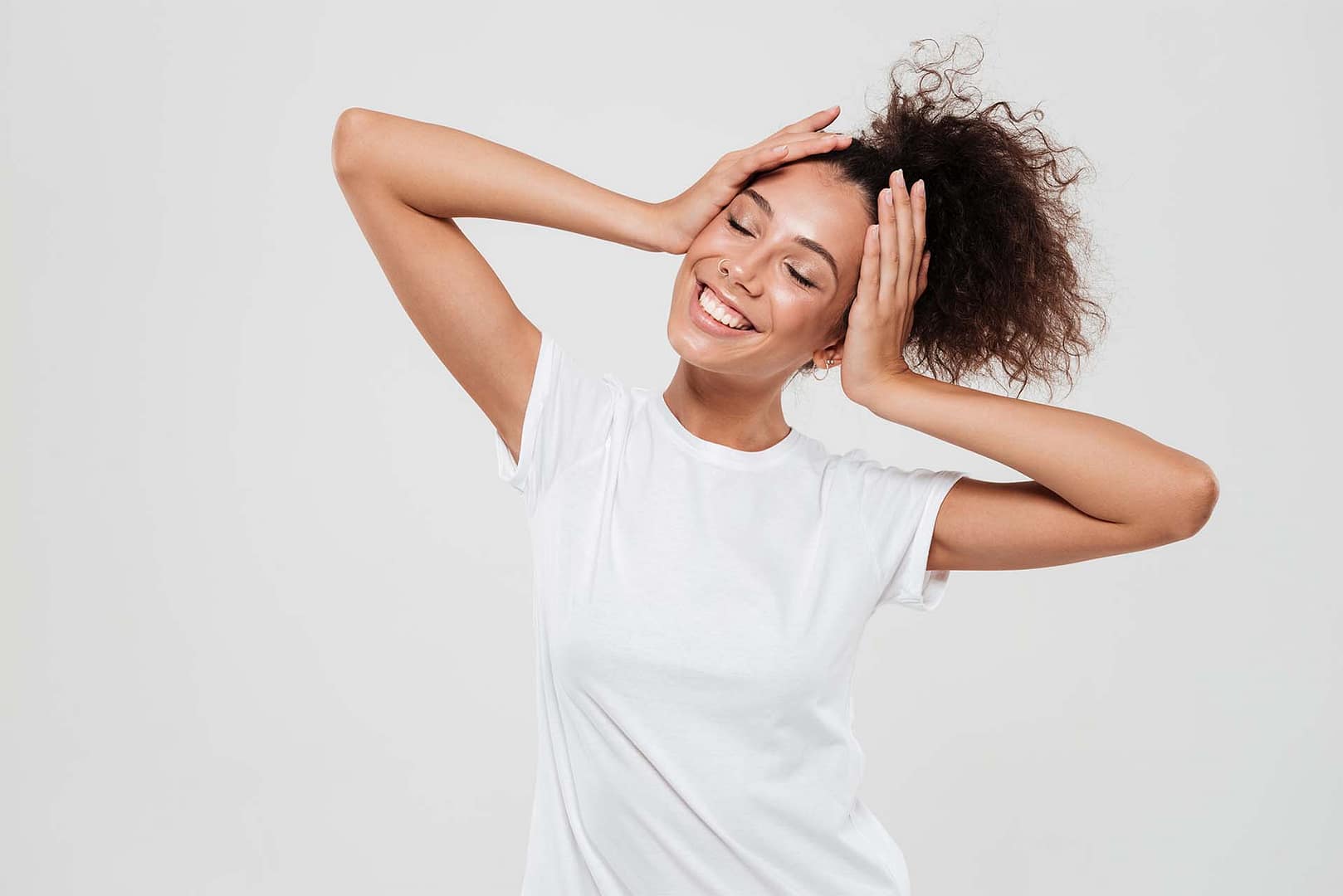 Pleased woman with closed eyes holding hands on head